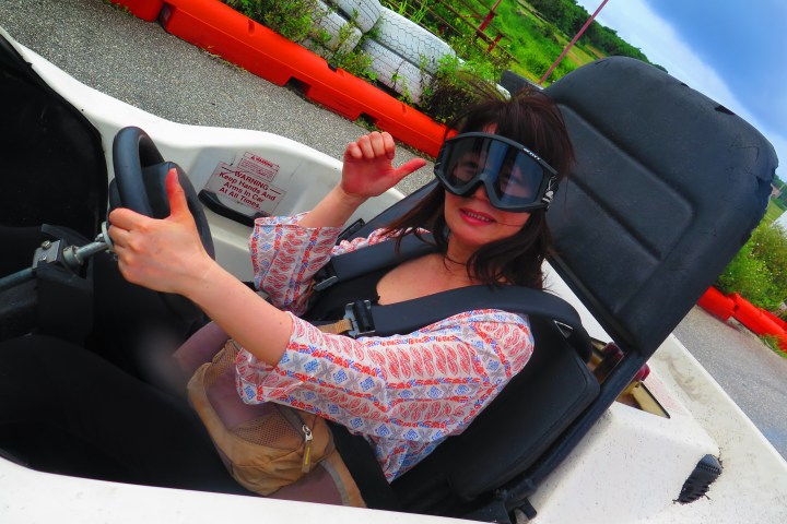 A woman giving the thumbs up while driving her go-kart