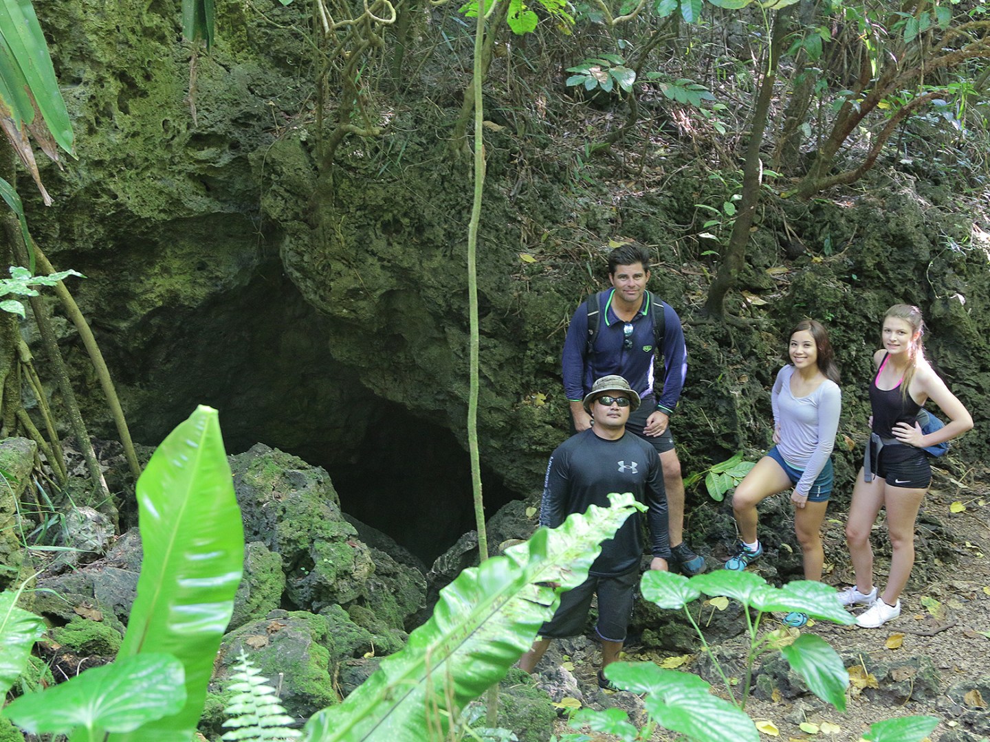 People posing out the opening of a cave