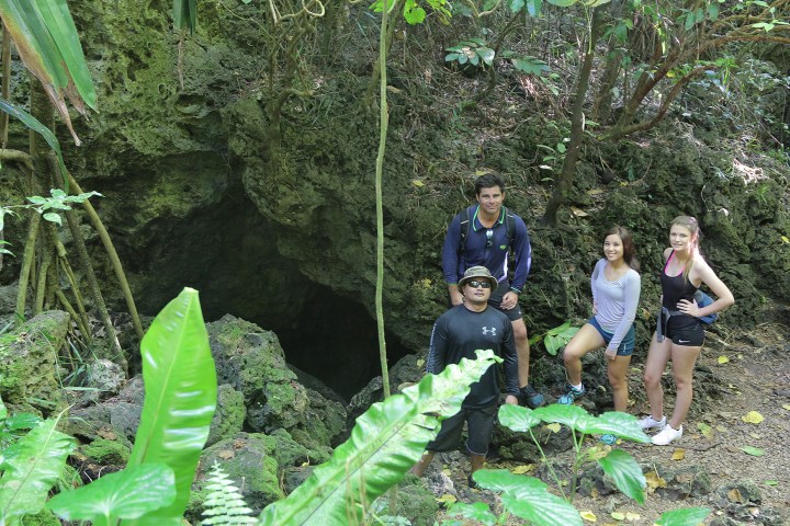 People posing out the opening of a cave