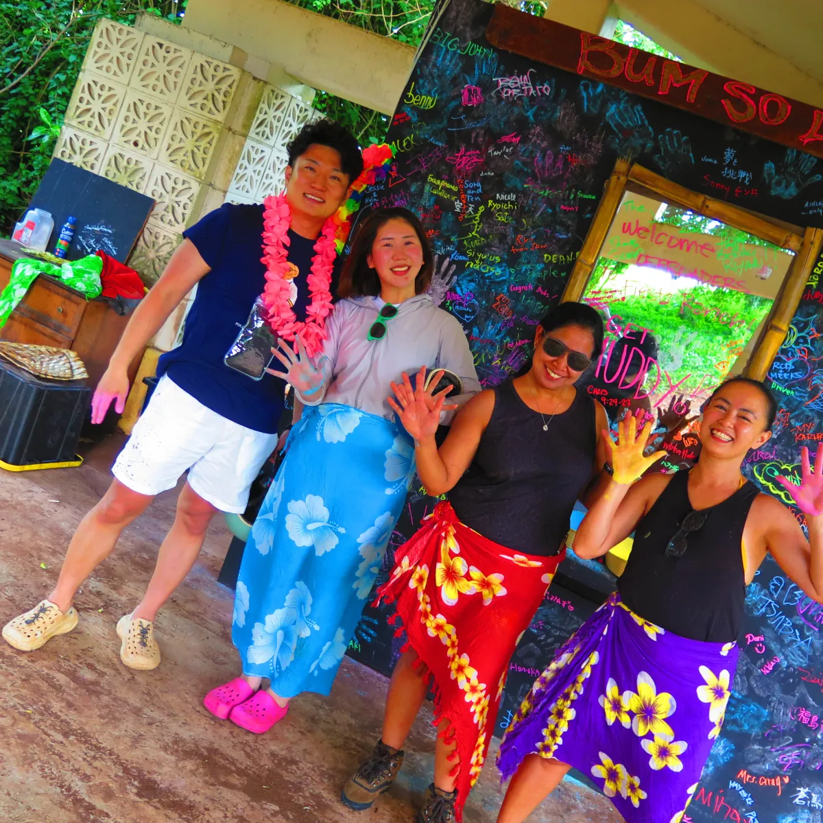Four people in colorful outfits posing with paint-covered hands.