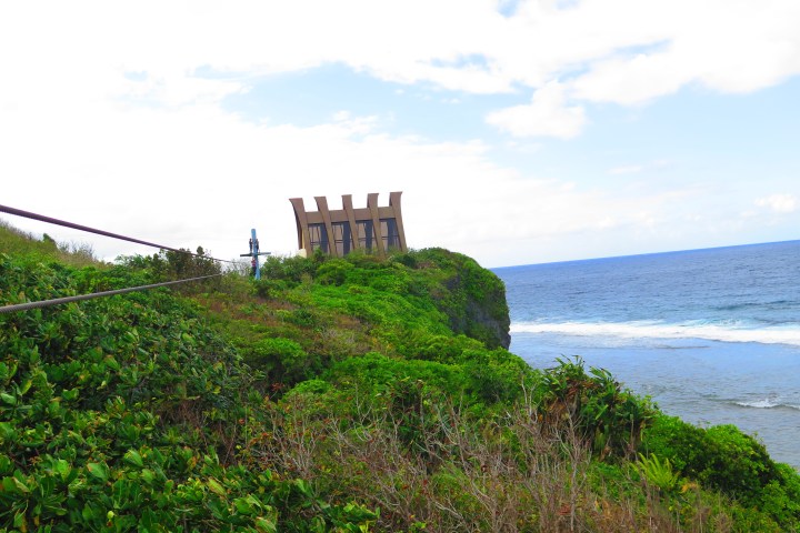 Cliffside building with green vegetation and ocean view.