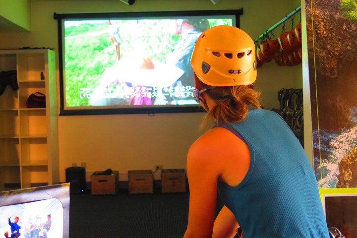 Person in helmet watches video in a room filled with adventure gear.